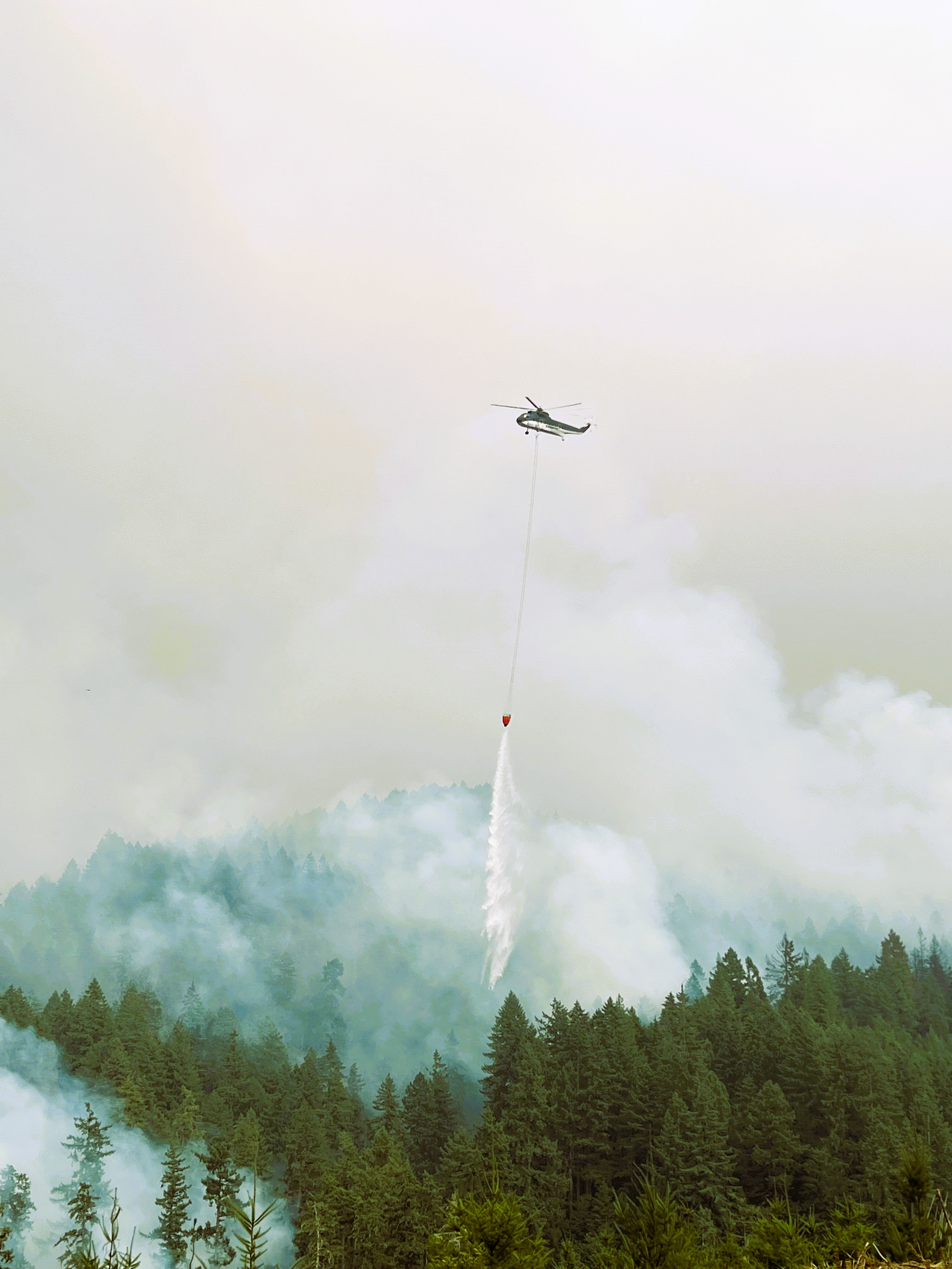 Image of helicopter dropping buckets of water on fire.