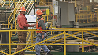 Image of two workers in a factory wearing hadhats.