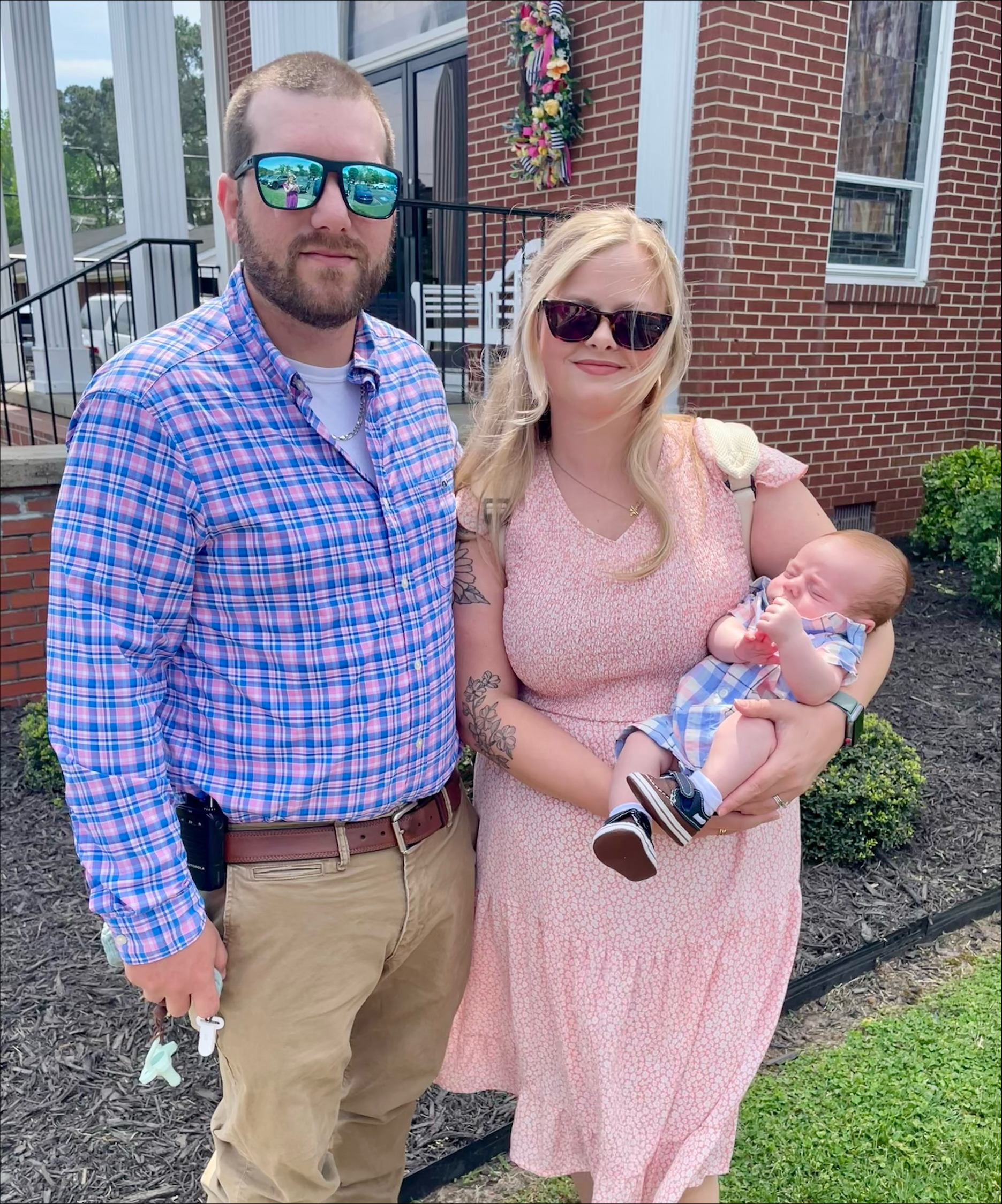 Image of Gentry and his wife and young child. Gentry is standing to the left while his wife, Carmen, is to the right and is holding their infant child.