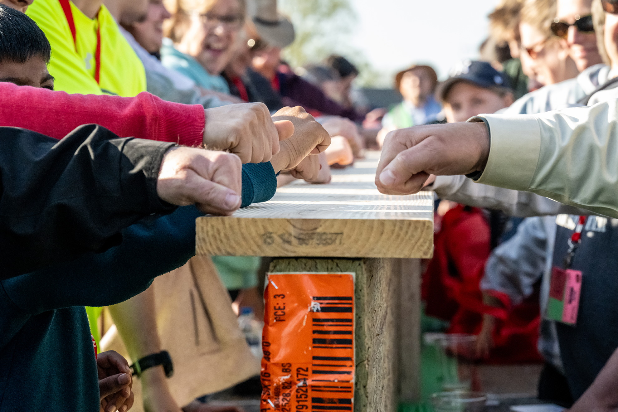 Image of people knocking on Weyerhaeuser lumber to set World Record for simultaneous knocking. There are several fists knocking on the wood.