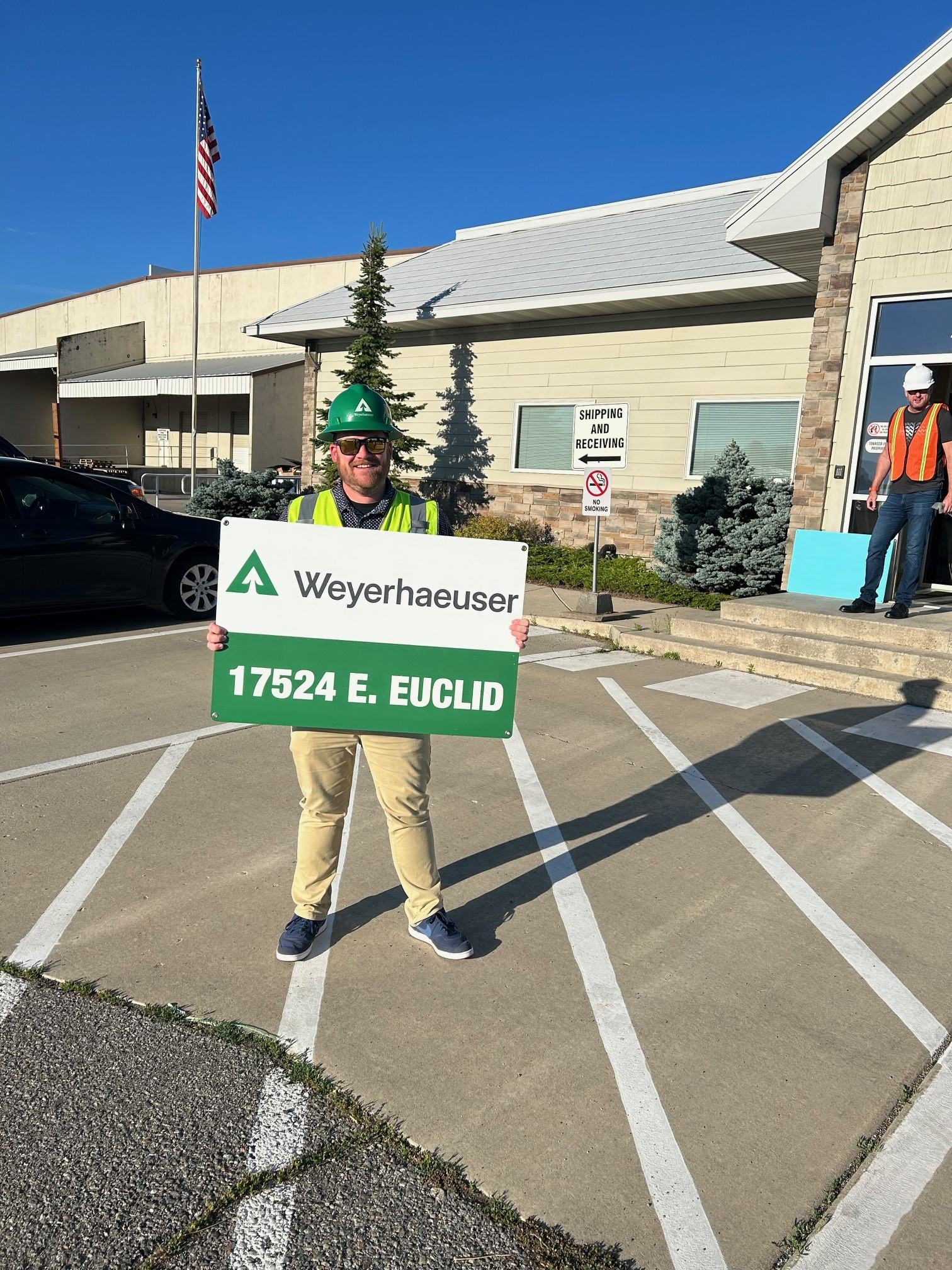 Image of area general manager Tom Moran standing outside the Spokane Distribution Center while holding a sign for the distribution center.