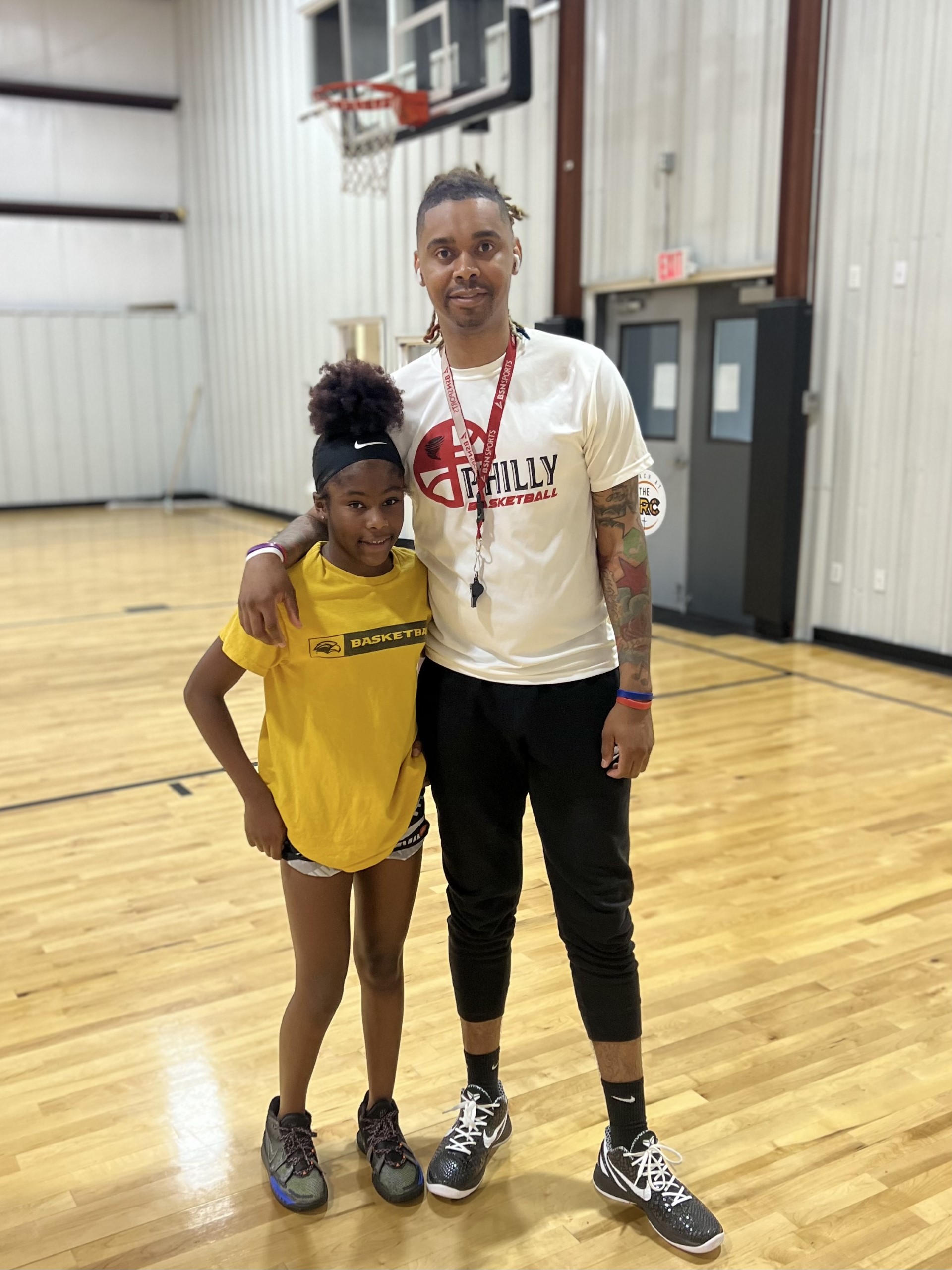 Image of Jacob Boler with a child he coaches during a Saturday basketball training clinic.
