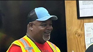 Image of Erick Cooper, who is wearing a blue baseball cap and a yellow safety vest.