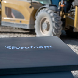 Image for insulation and weatherization, showing a styrofoam sign in the foreground of a tractor.