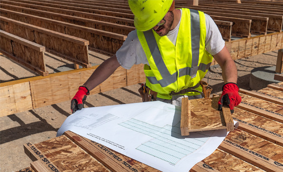Image showing a worker in PPE examining blueprints.