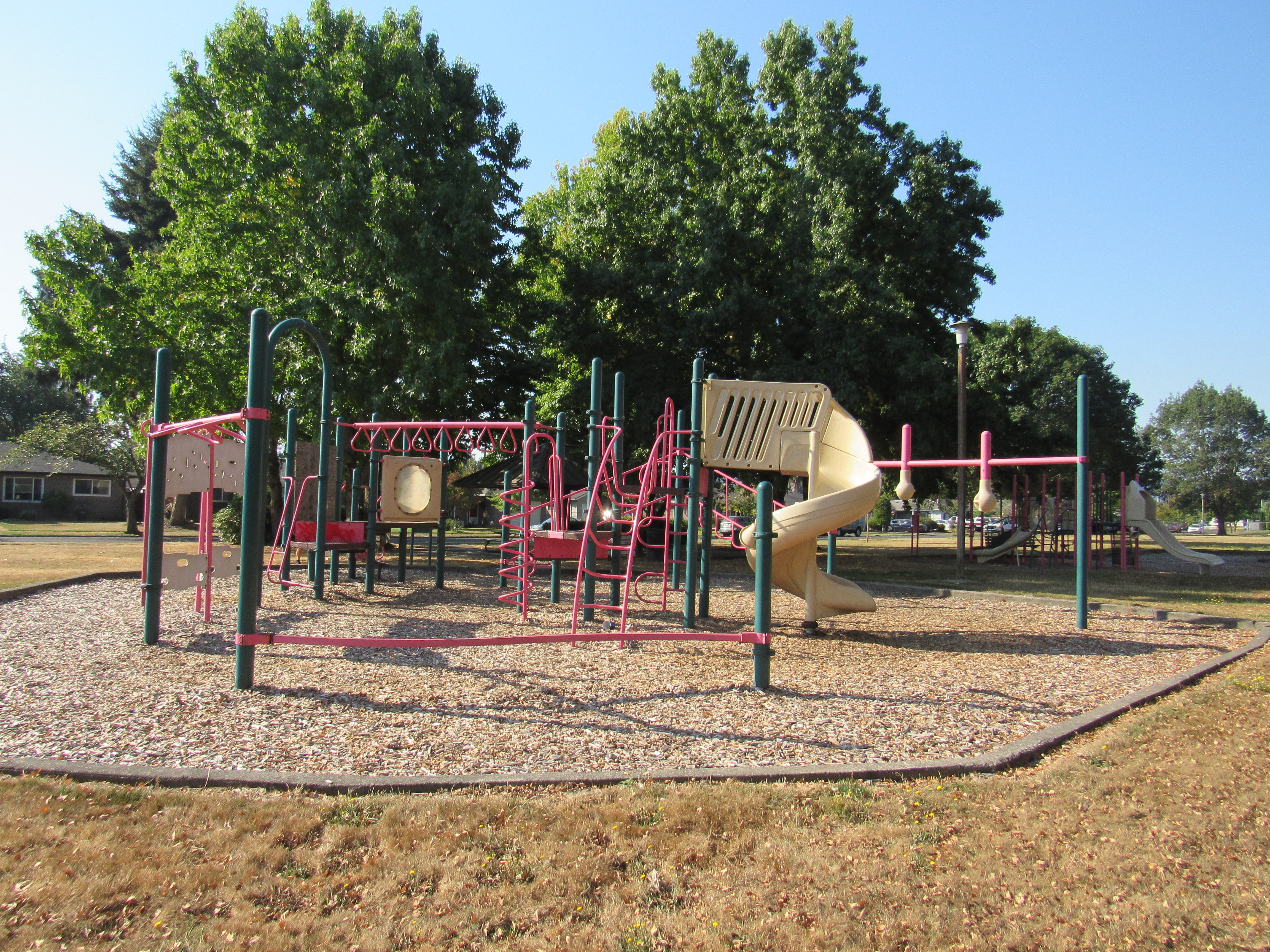 Image of the Cloney Park playground in Longview, Wash. There are several bars for kids to climb on and swing from, as well as a twisting slide.