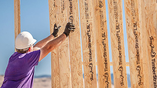 Person holding up framed wall under construction.