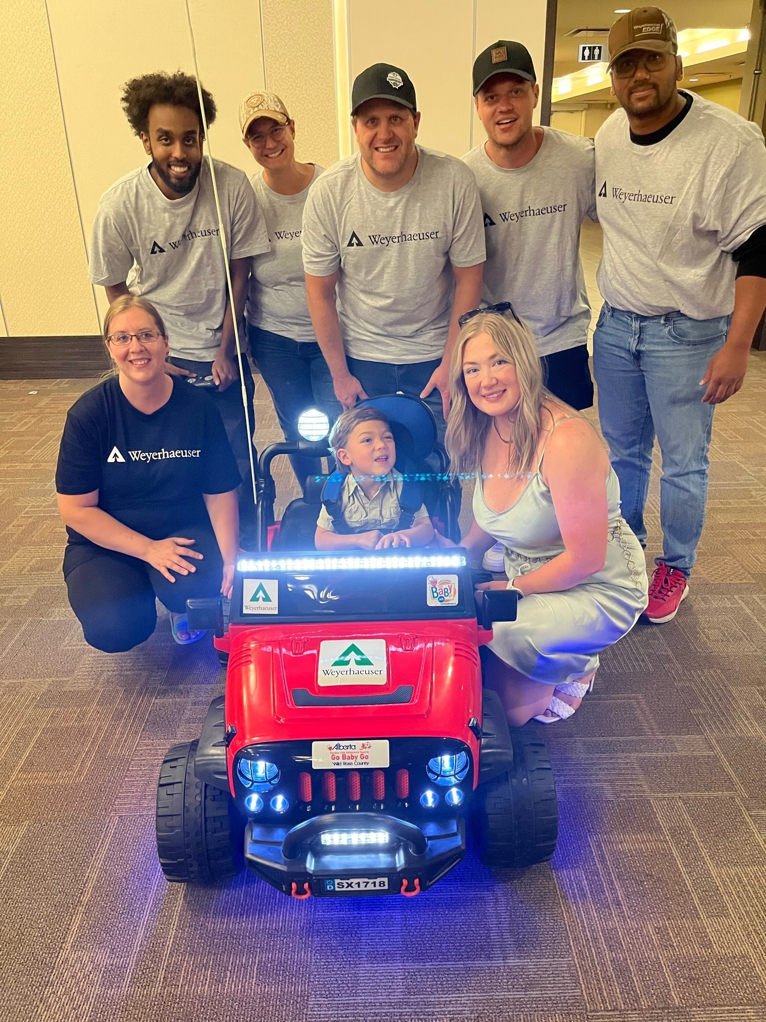 Image of Noah with his mom and the volunteer group that built his car.