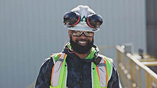Image of a worker wearing a Weyerhaeuser-branded hardhat wearing safety googles and with ear protection worn over his head.