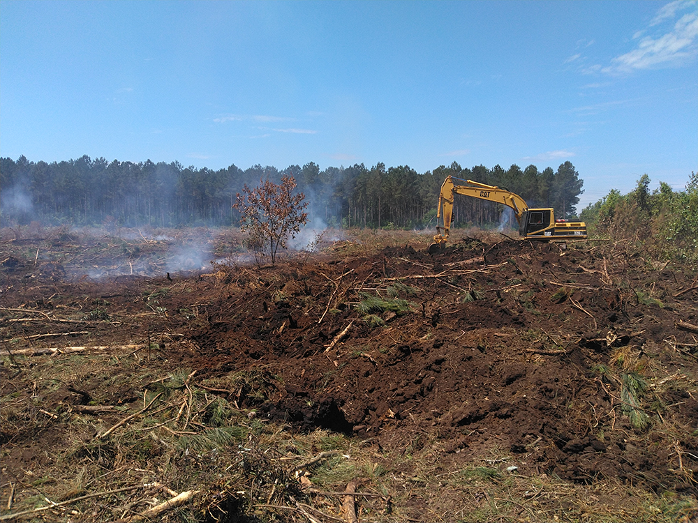 Image showing a piece of heavy machinery digging out the fire below the surface of the soil.