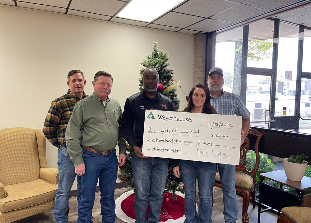 Courtney McKee and local leaders presenting a large ceremonial check for $100,000 to support tornado disaster relief in Idabel.