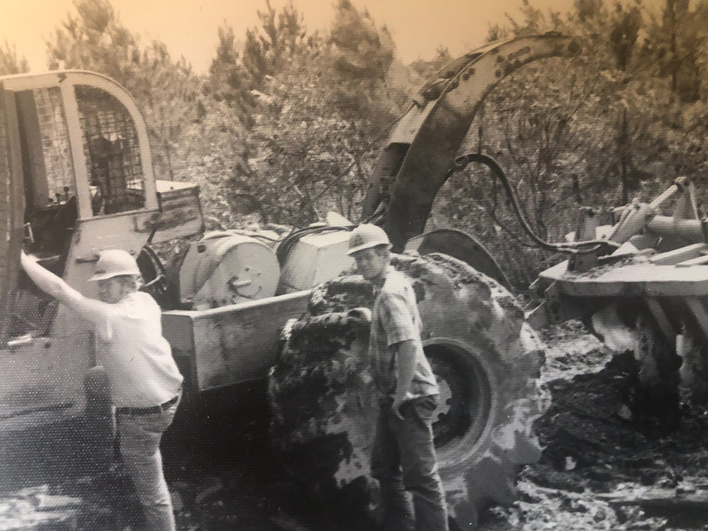 Black and white image of Don with his twin brother Lon as they are stepping onto a large piece of machinery to prepare the ground for reforestation.