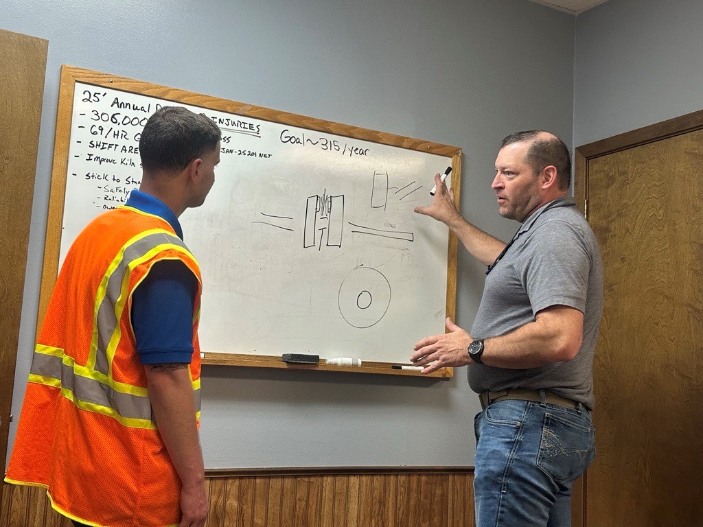 Image of Robert standing in front of a white board while talking with Sawyer Upchurch, a leadership development professional.
