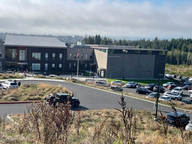 Fog rises off the Pacific Ocean, which is now far below the new Seaside schools.