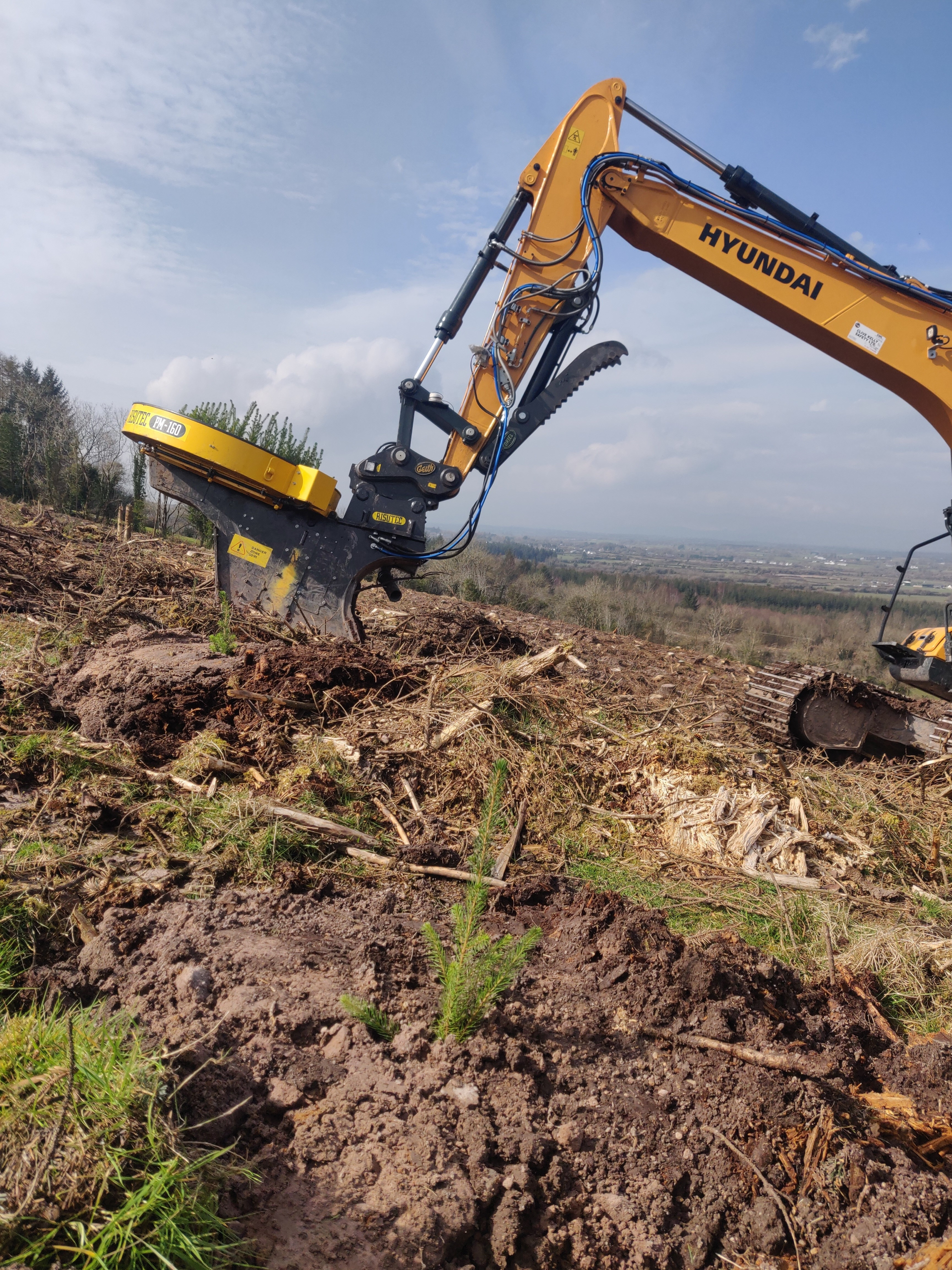 Tyler's curiosity around what can be adapted from other fields and from forestry practices in other countries drove him and his team to experiment with an automated seedling planting attachment fixed on an excavator to eliminate some of the laborious manual planting. Notice the seedling tops sticking out of the circular attachment.