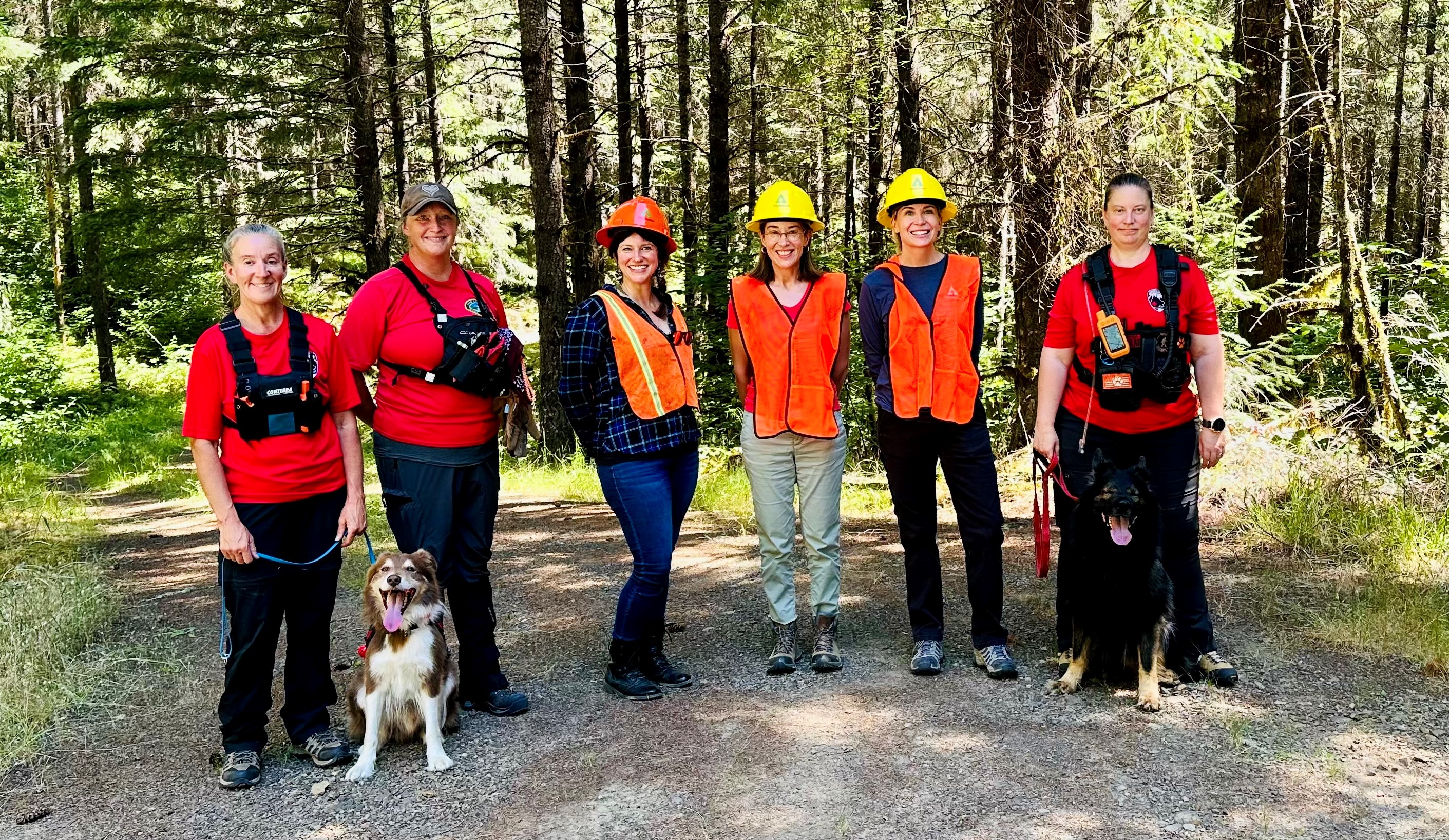 A group of Weyerhaeuser employees stand with the dog trainers and Yeti, a K9 trainee, in the Oregon forest.