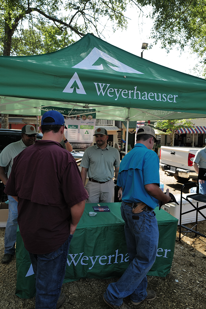 Image of people standing at the Weyerhaeuser tent at the Neshoba County Fair in Philadelphia, Miss.