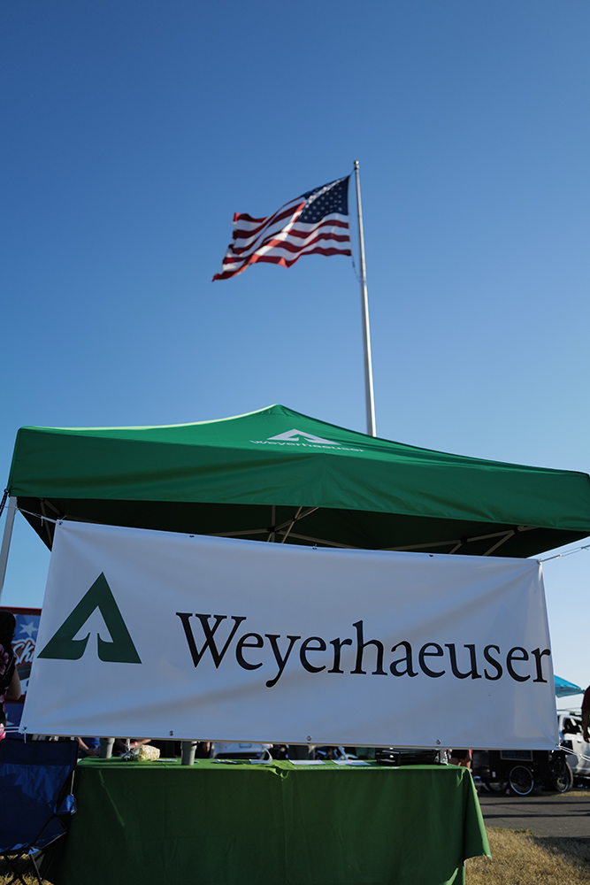 Imagte of the Weyerhaeuser tent on the concert grounds, with the American flag rising in the background.