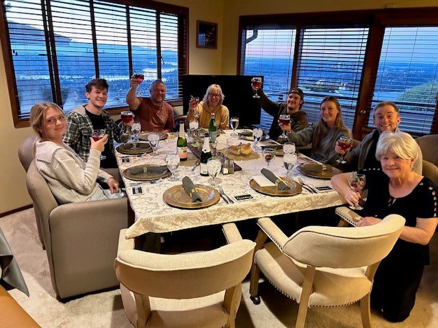 Image of several people surriounding a table and holding their glasses up. 