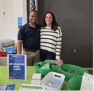 Courtney McKee and Shaun Clark standing together at a career fair booth in Idabel, Arkansas.