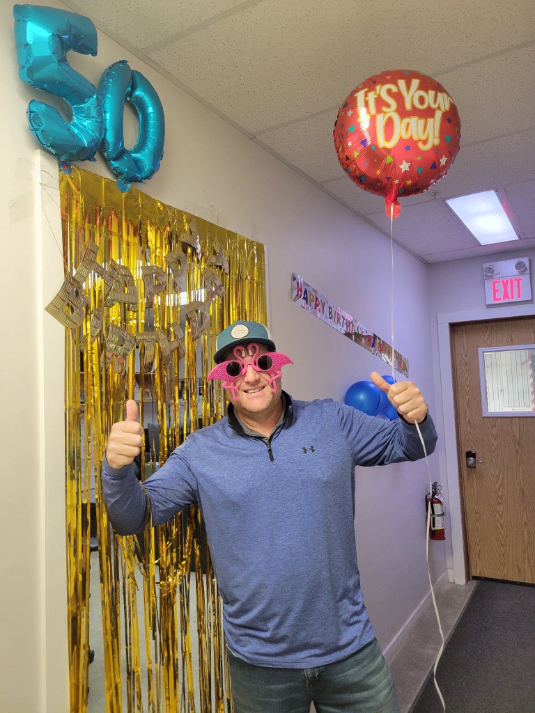 Image showing Matt in a blue shirt with flamingo sunglasses and birthday balloons.
