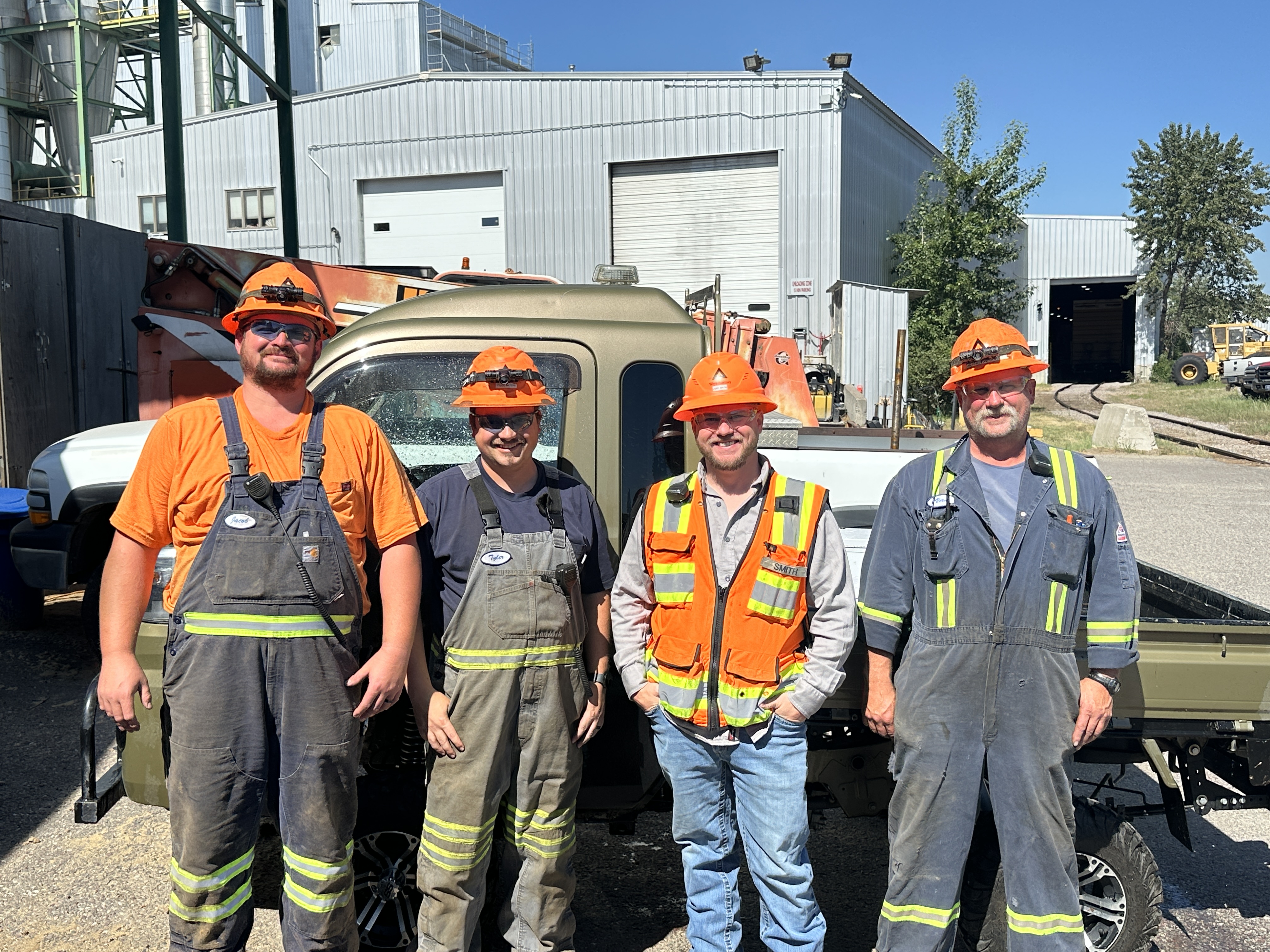 Image of men from the Columbia Falls steam who worked to improve air compressor reliability. The men are all wearing PPE and are standing in front of a truck.