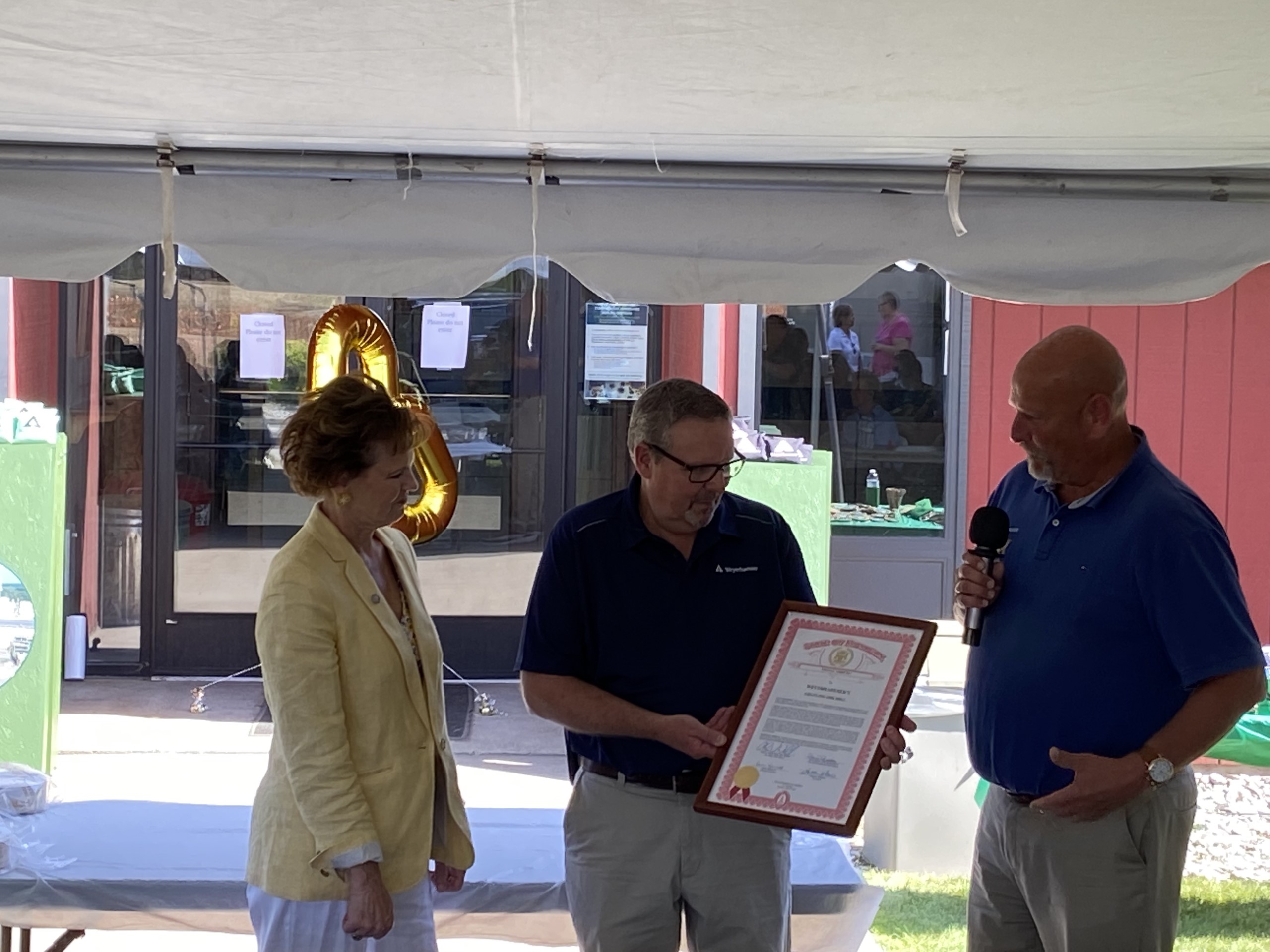 State Rep. Dare Rendon (left) and State Sen. Curt VanderWall (right) present a Tribute certificate to Bruce.