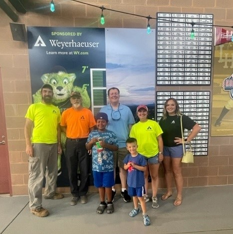 Andrew Brown, Andy Laviner, Mike Becue, Regan Corey and Katie Jordan, silviculture forester in Lynchburg, pose with Andy’s grandson Jordan and Andrew’s son Killian in front of the growth chart the Lynchburg team sponsored at the ballpark a few years ago.