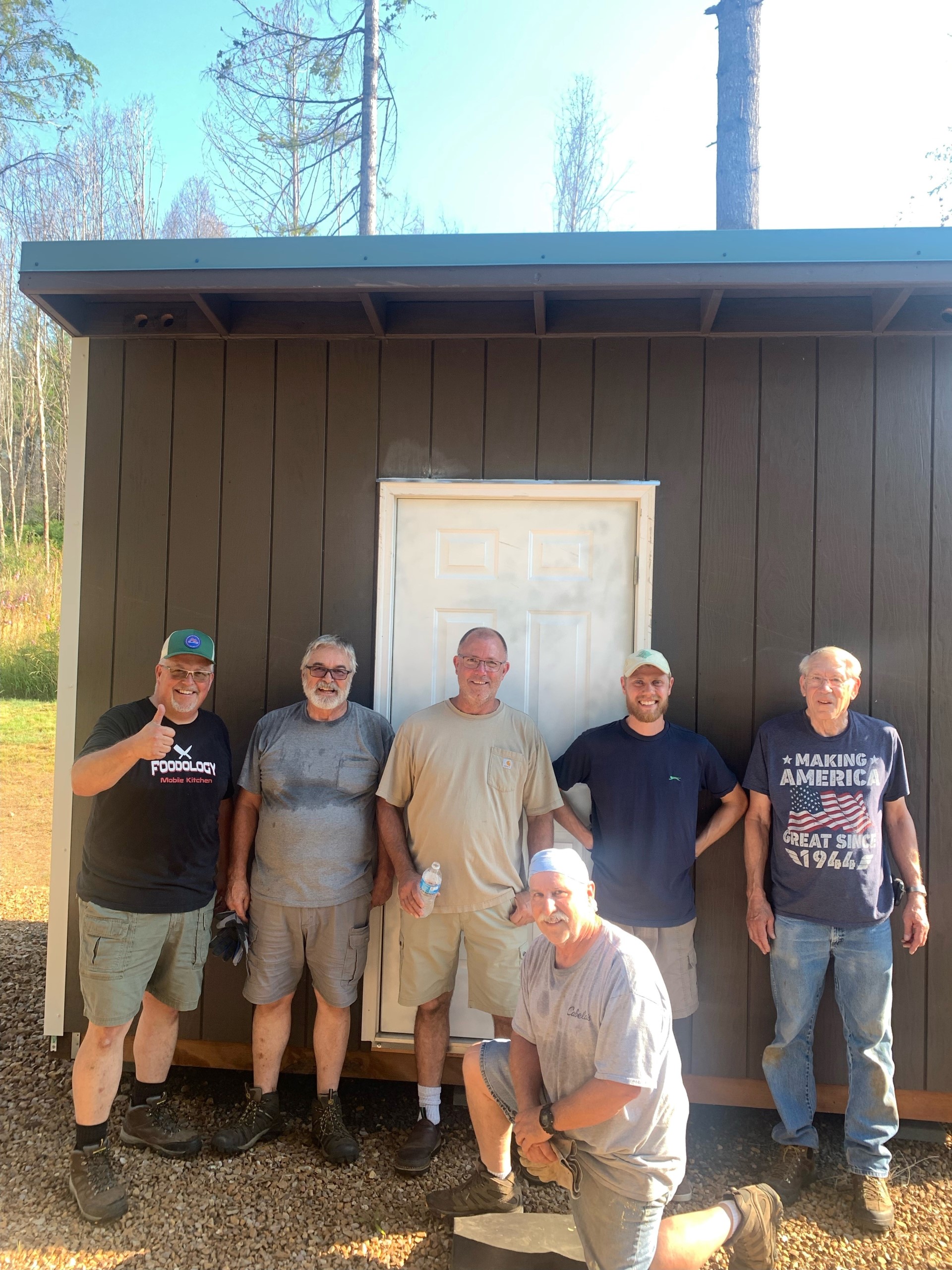 Volunteers take a moment to celebrate the completion of the 100th shed. The Santiam Canyon Shed project aims to erect at least 150 sheds for local residents waiting to reconstruct their fire-damaged homes.
