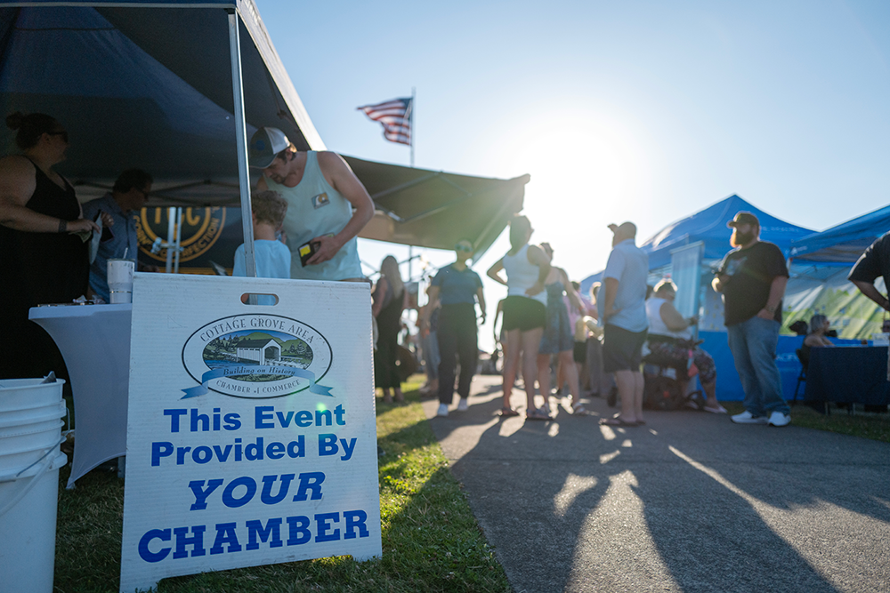 Image of the crowd at the concert with tents and a sign in the foreground that says "This event provided by your chamber."