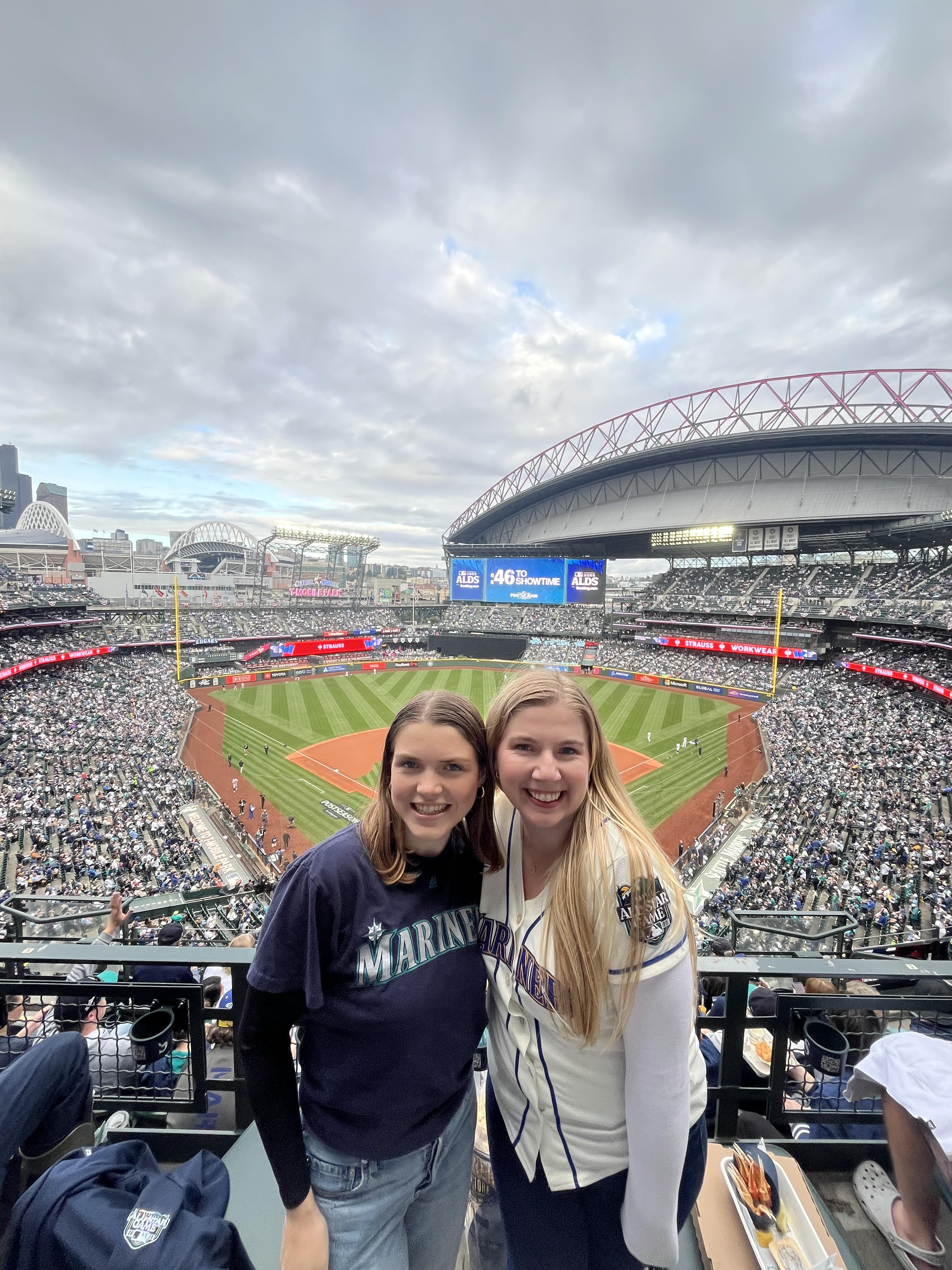 Image of Ashely and a friend cheering on the Mariners at a baseball game.