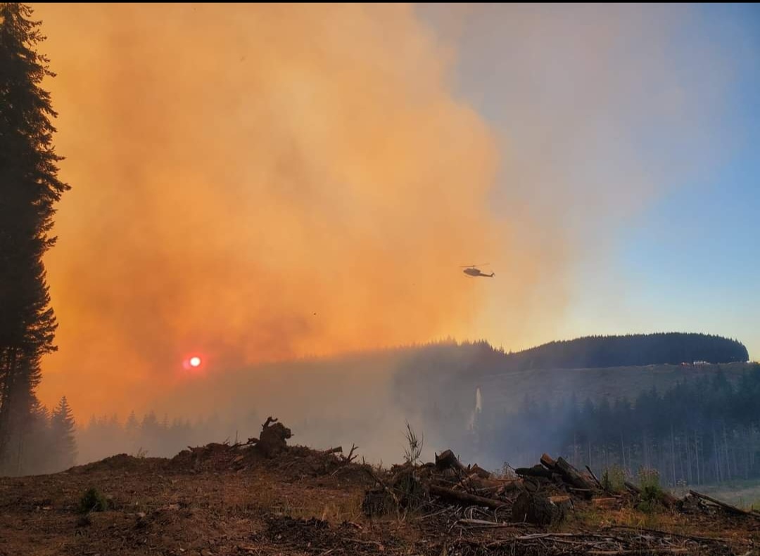 Image of smoke from the Lane 1 fire with a helicopter visible right of center.