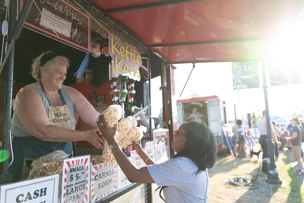 Image of a customer getting bags of popcorn from a concession stand at the concert.