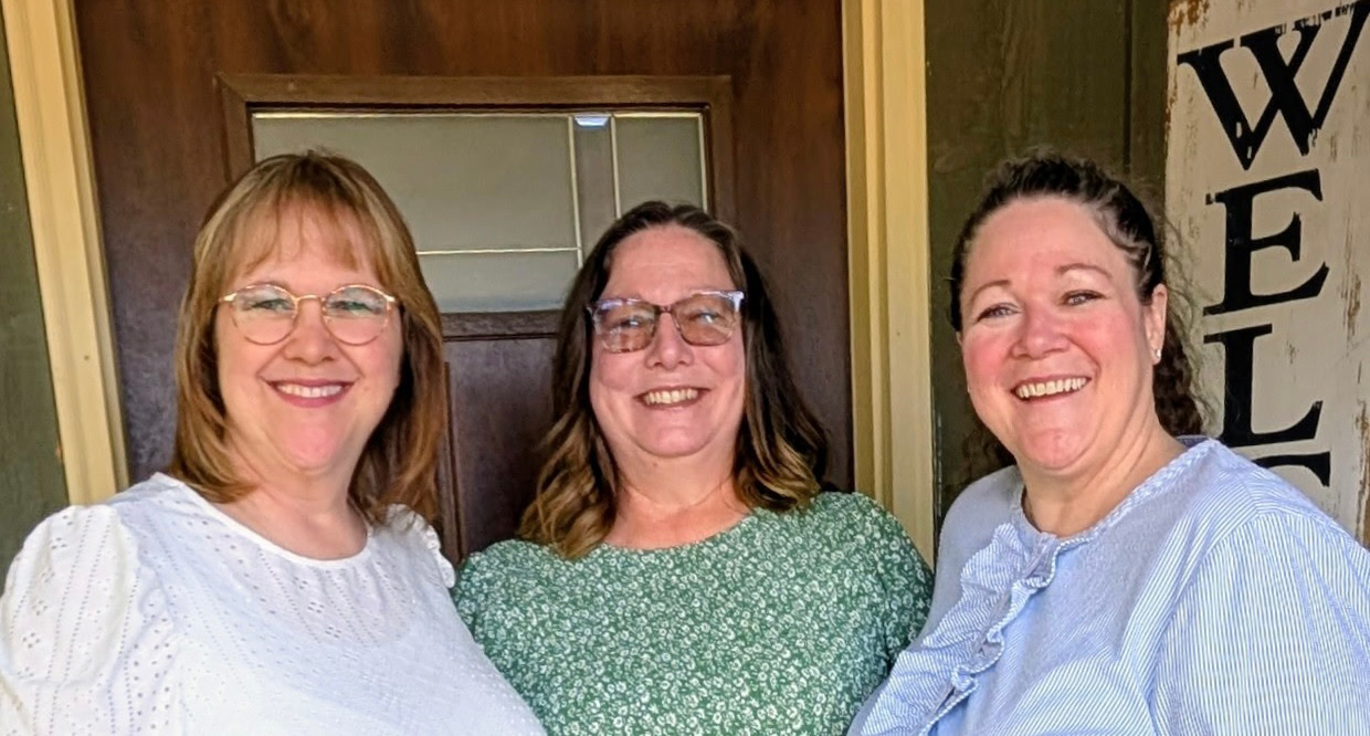 Image of Torri with her college roommates. They are standing three across in the image with Torri on the right side, wearing a purple blouse.