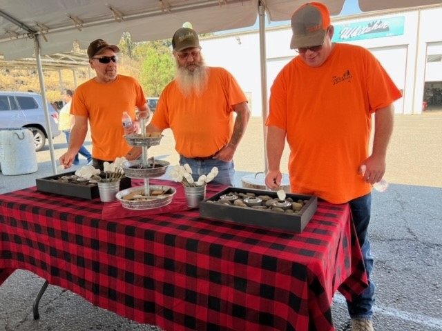 Image of three Whitaker employees in orange shirts as they enjoy a catered lunch.