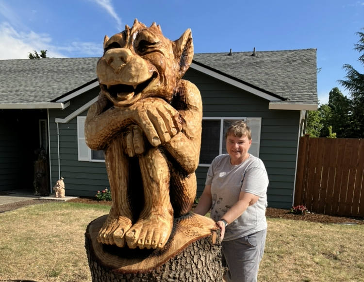 Image of Jann with a statue carved out of a stump in her front yard.