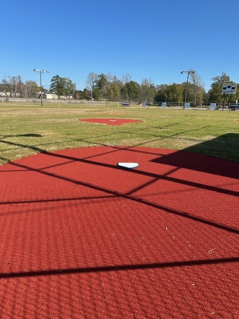 Image of the newly renovated field, with red nylon around home plate and the pitcher's mound on the smaller field and freshly cut grass.