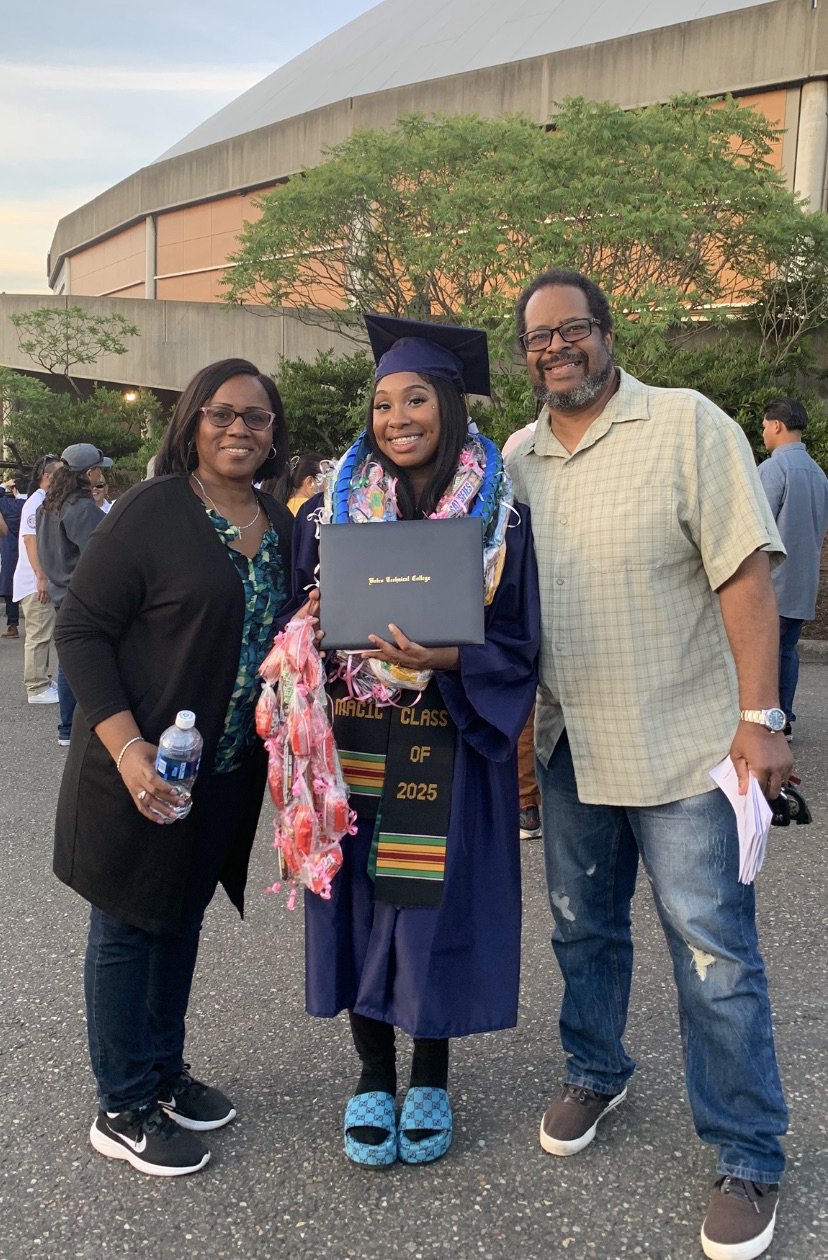 Image of Teresa and her husband Sheldon standing on either side of their daughter, Dominique, at her college graduation.