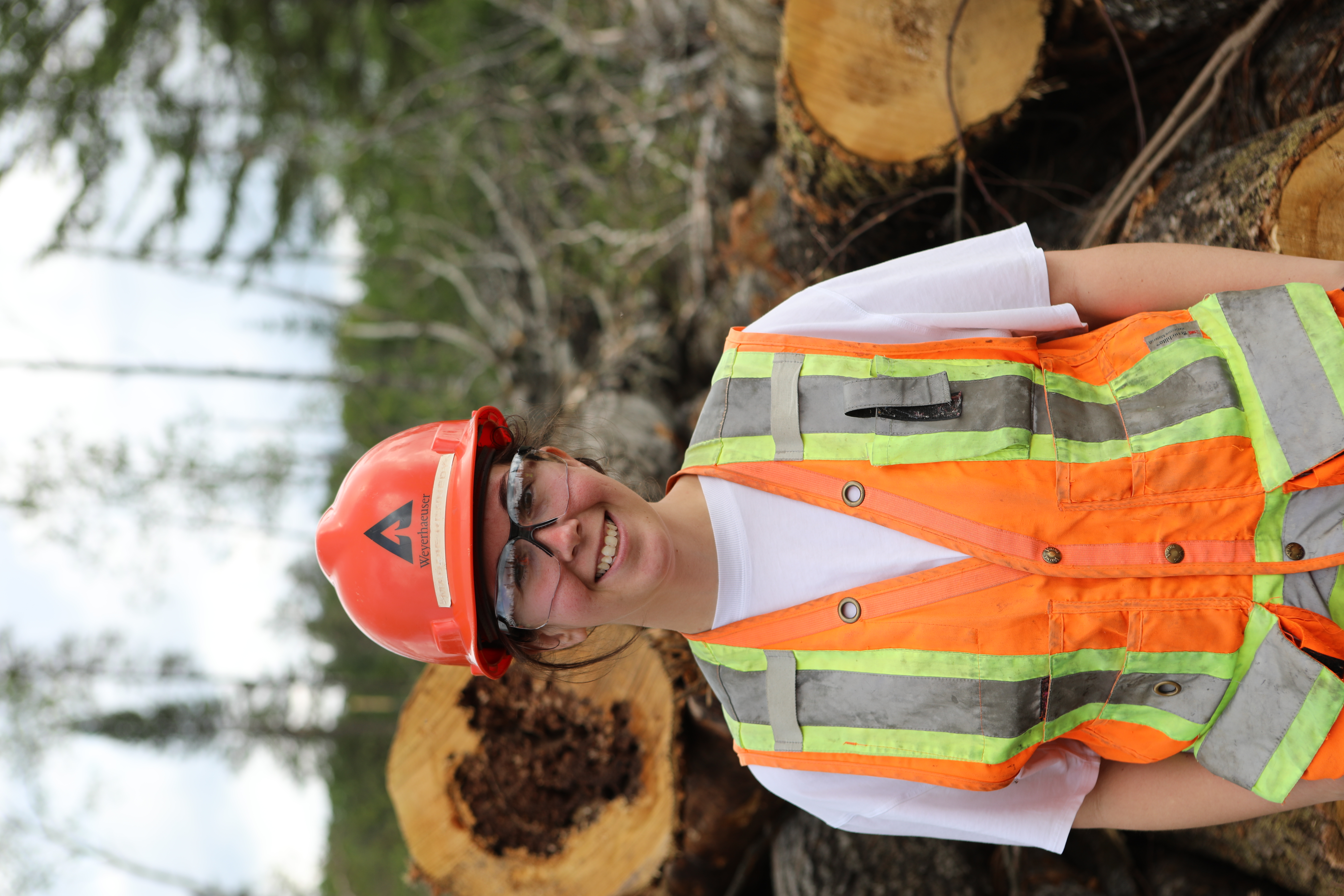 Image of Maddie with freshly harvested poplar logs.
