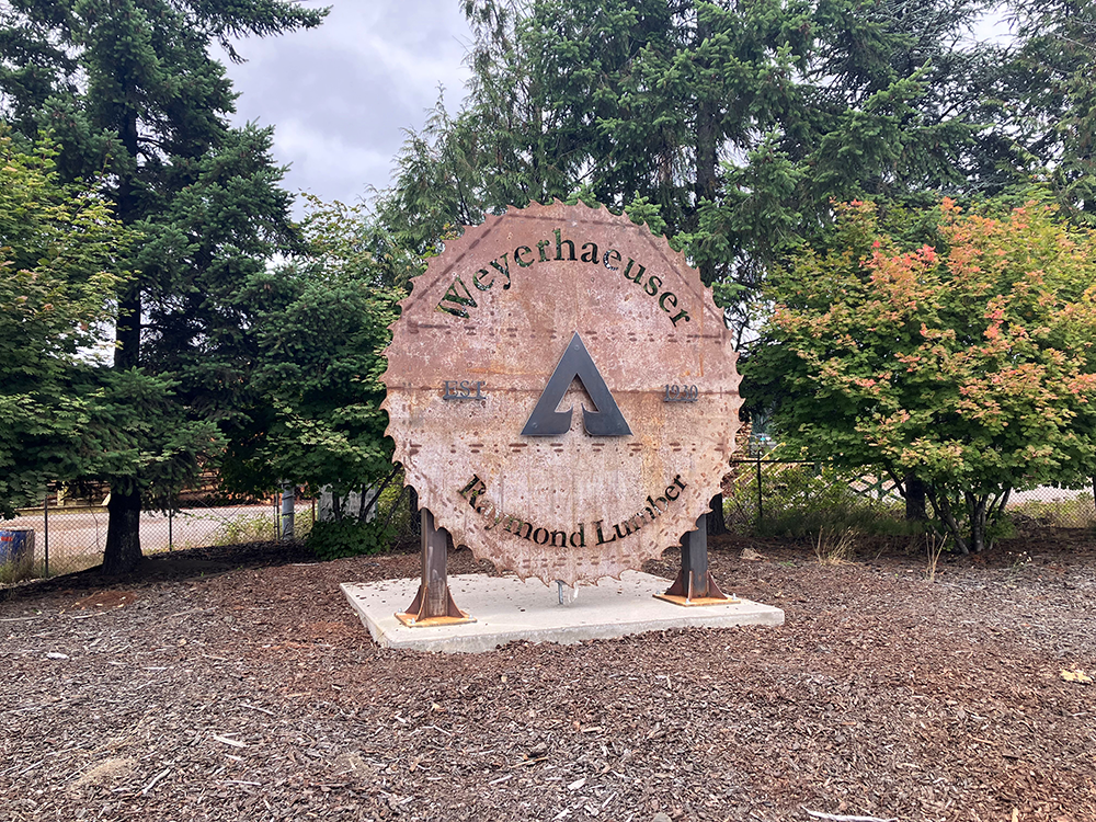 A large carving of a saw blade welcomes visitors to the Weyerhaeuser Raymond Lumber yard.