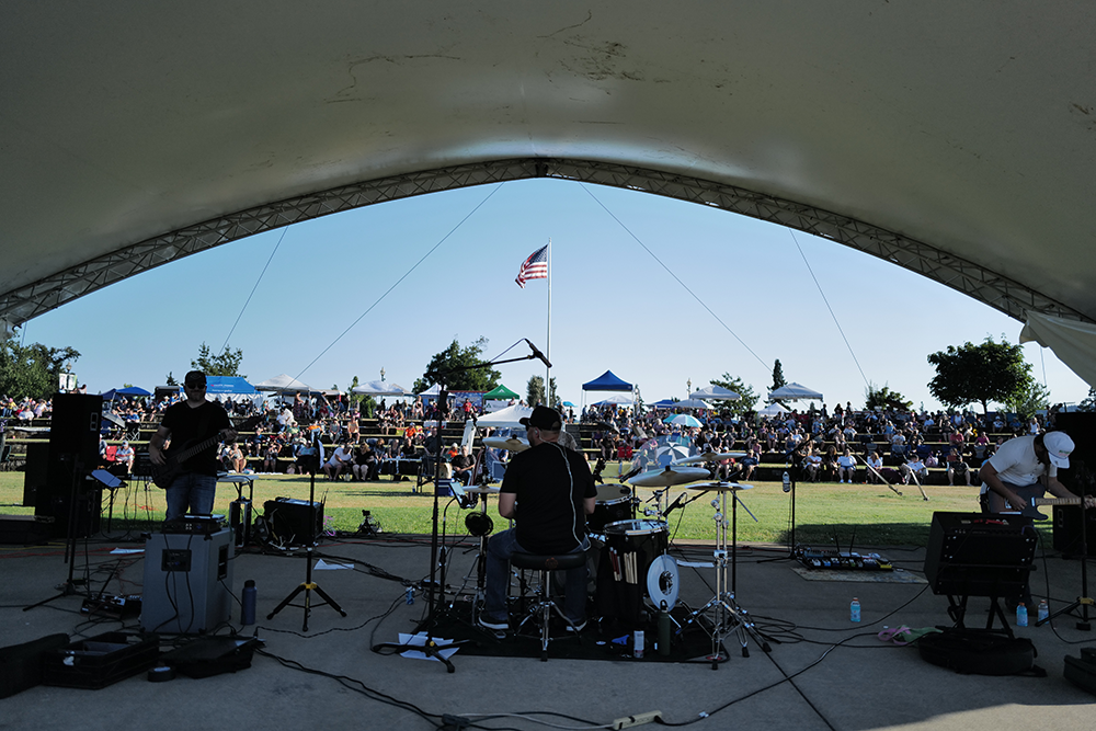 Image of the band playing at the concert, seen from behind.
