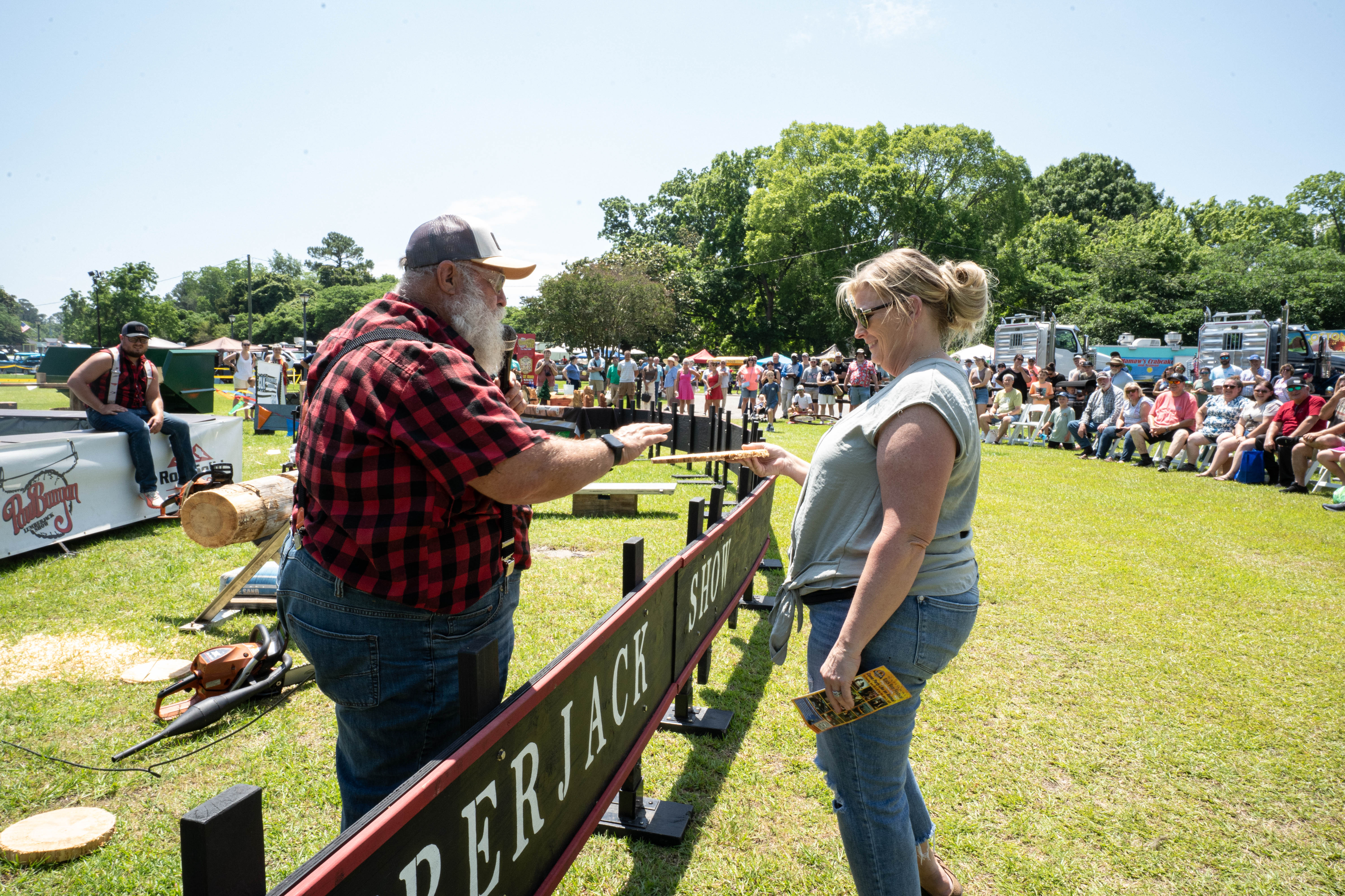 Image of a woman receiving a freshly-cut piece of wood from a lumberjack show that took place at the festival.