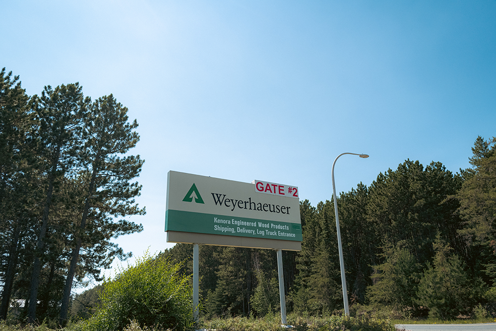 Image of a sign showing where the Weyerhaeuser plant is located with trees behind and next to it.