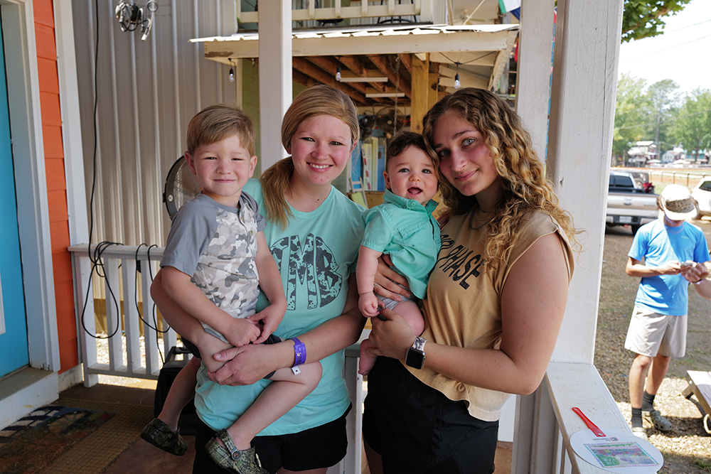 Image of two women holding two young children at the Neshoba County Fair in Philadelphia, Miss.
