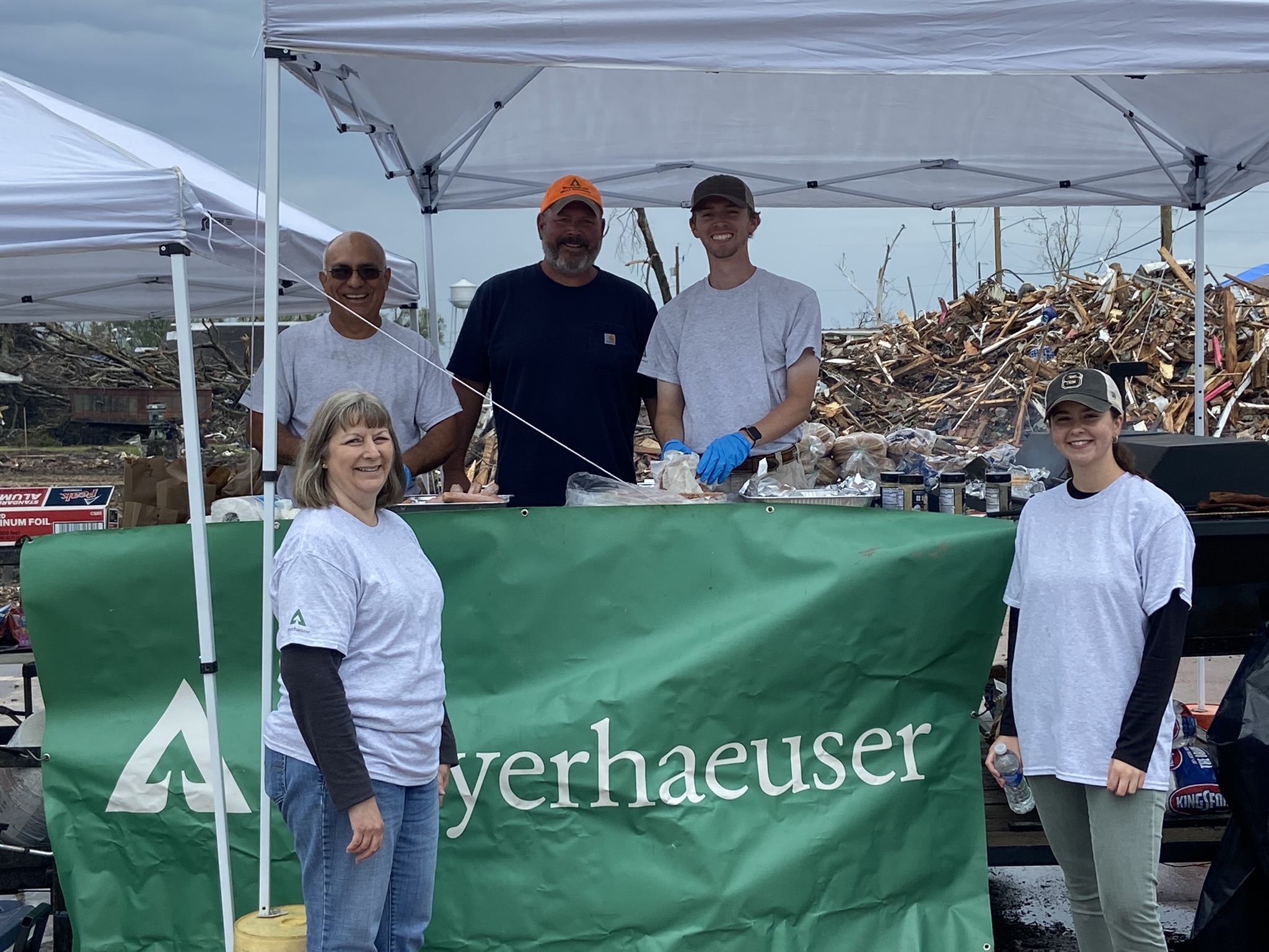 Image of Weyerhaeuser volunteers with debris from the tornado in the background.