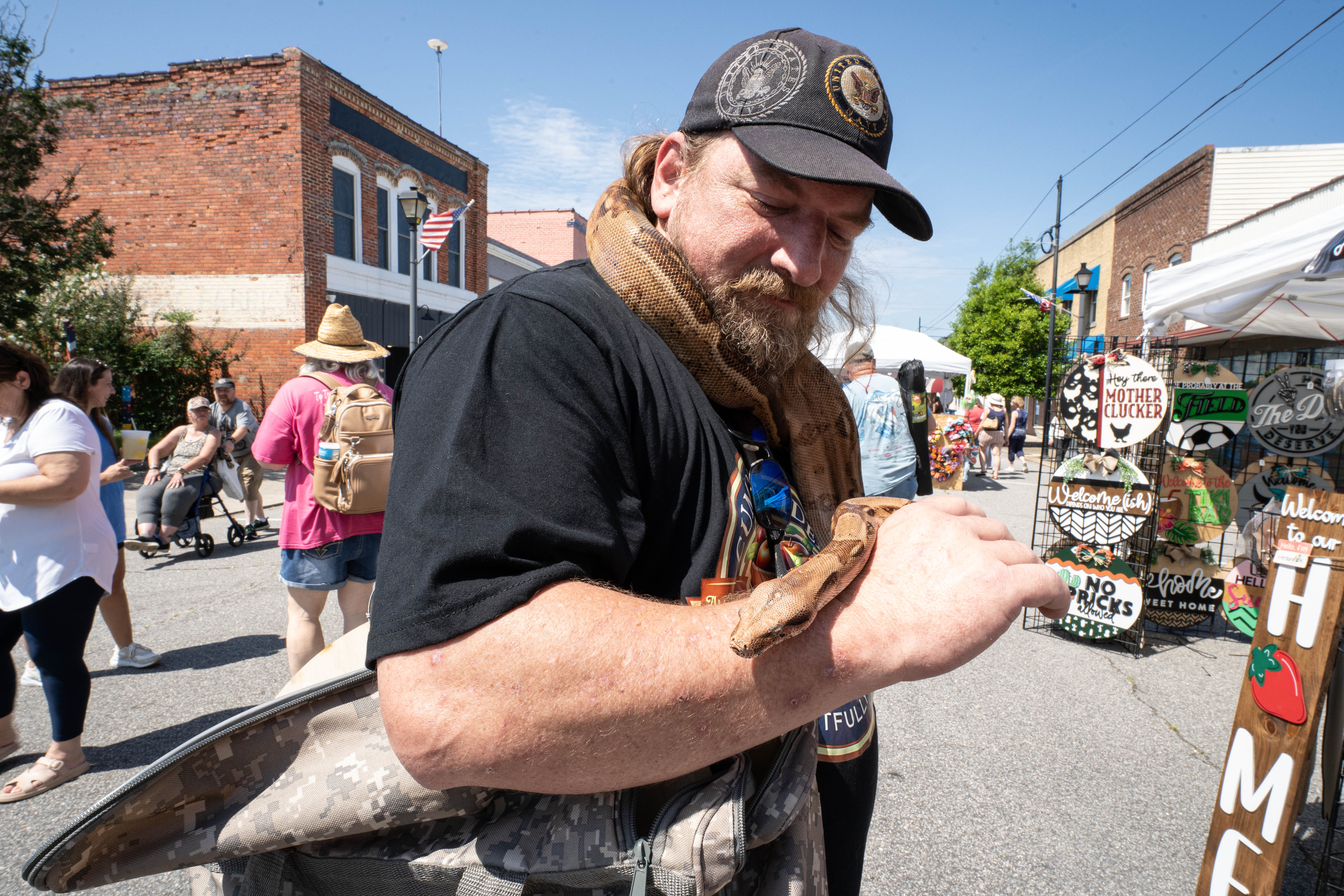 Image of a man holding a snake over his shoulders and arm at the Black Bear Festival.