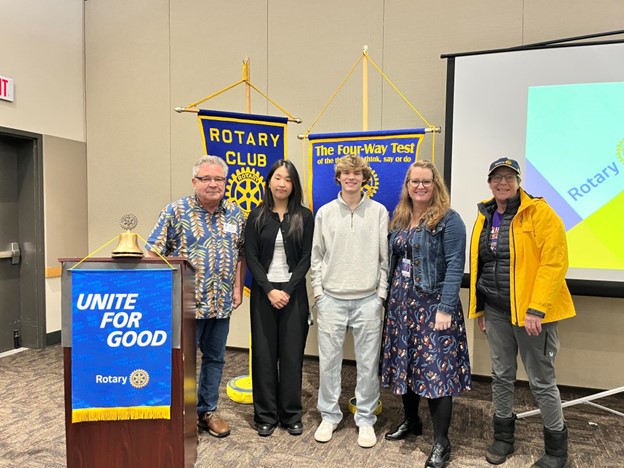 Image of Tim with several students on stage with a "Rotary Club" banner just in the background.