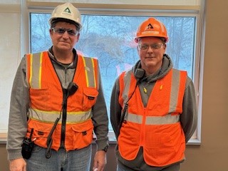 Tim and Chris Corder, Sutton Safety Manager, stand together. They are both wearing PPE, which includes hard hats, safety vests and goggles.