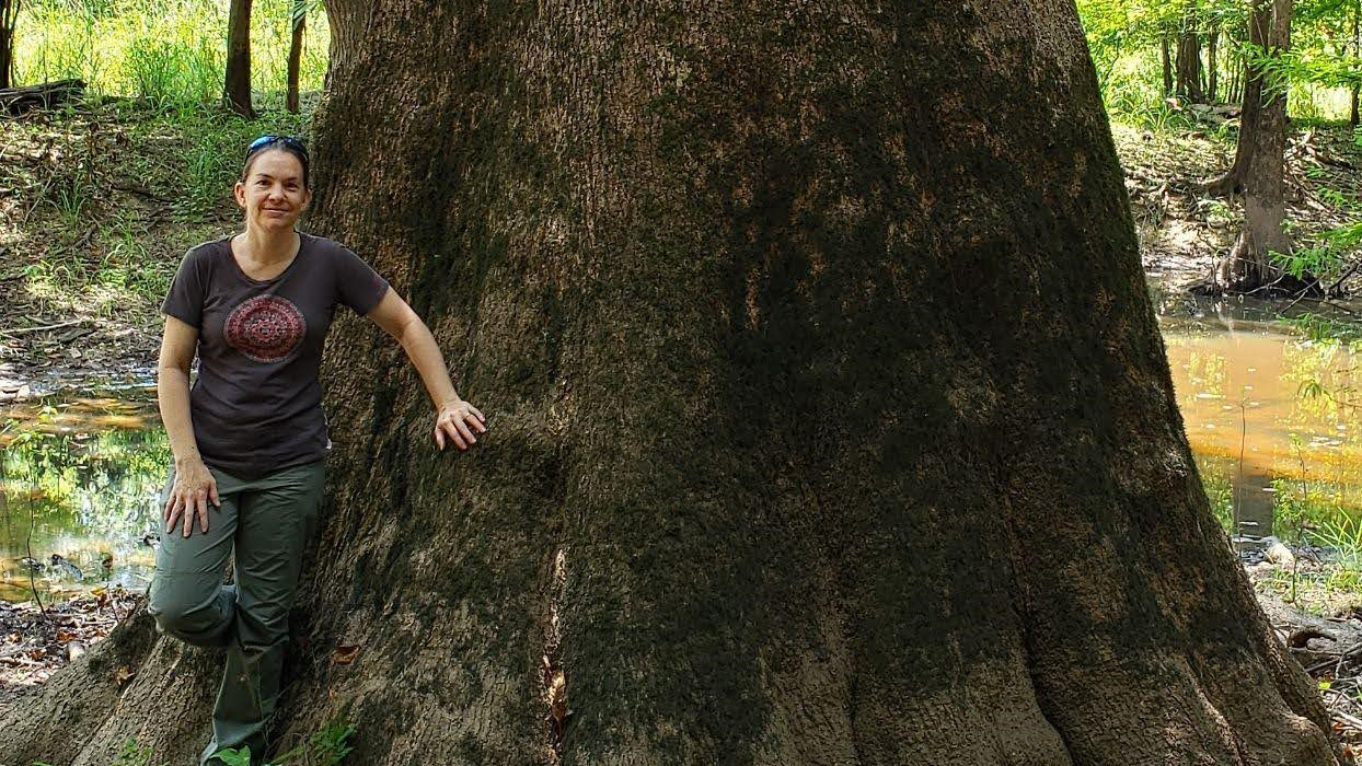Image of Zaina Gates standing near a massive tree on company property in Savannah, Georgia.